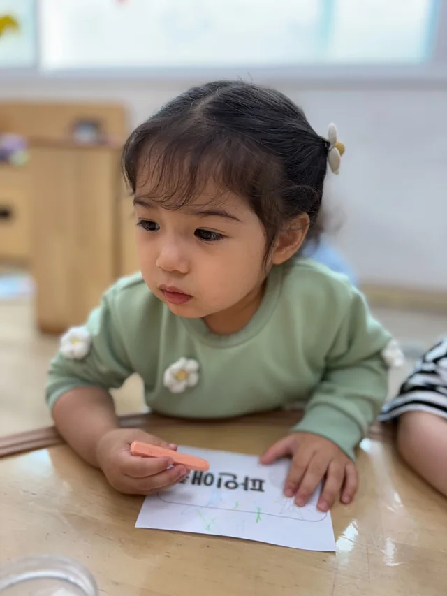 초록색 상의를 입고 교실의 활동에 집중하는 일린