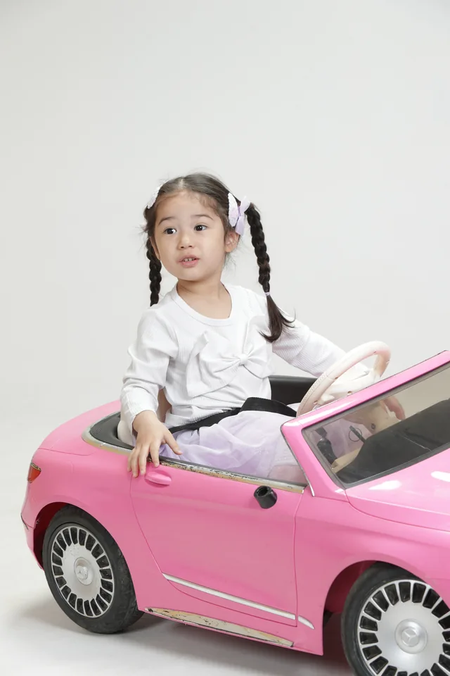 분홍색 자동차와 함께 포즈를 취하는 일린의 스튜디오 전신 사진